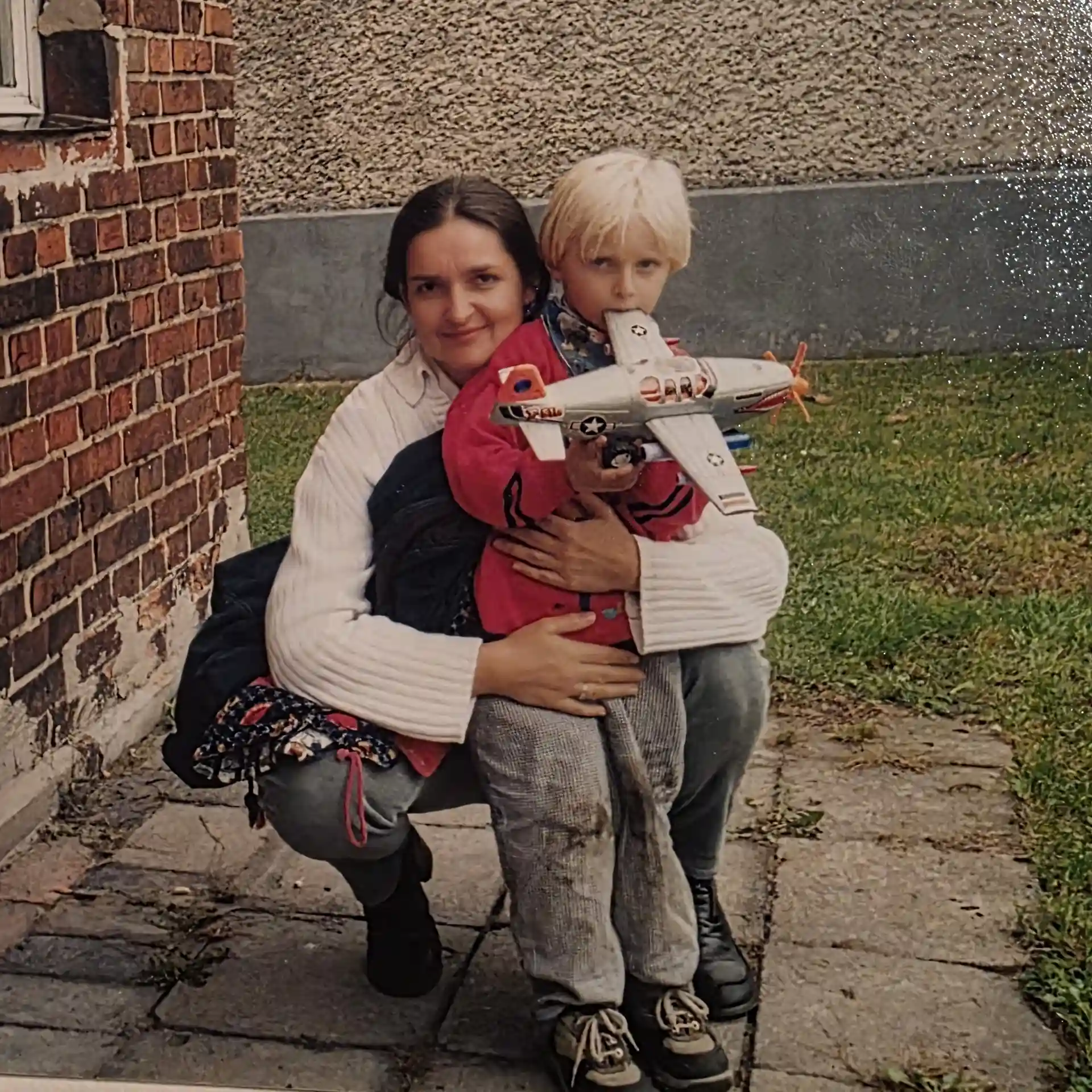 Julian mit Mama Julian im Arm von seiner Mutter und einem Flugzeug im Mund